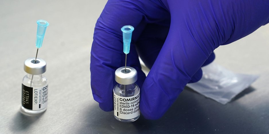Leere Impfdosen vom Biontech Impfstoff Comirnaty stehen auf einem Tisch im Labor.