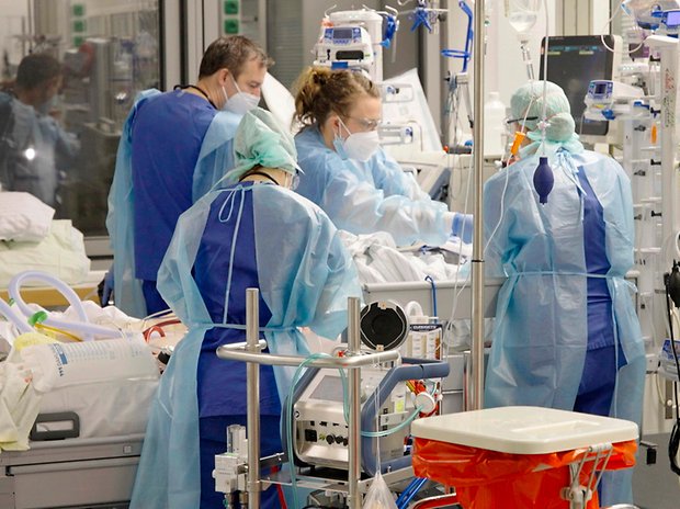 Ärztinnen, Ärzte und Pflegende auf der Corona-Intensivstation der Charité am Bett einer jungen Patientin.