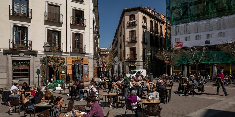 Menschen sitzen an der Sonne auf der Terrasse eines Cafés inmitten der Corona-Pandemie.
