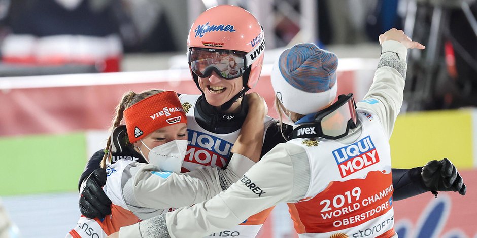 Katharina Althaus (l.) und Anna Rupprecht bejubeln mit Karl Geiger den Gewinn der Mixed-Weltmeisterschaft.