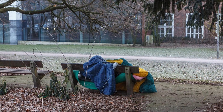 Ein Obdachloser hat sich auf einer Parkbank ein Lager eingerichtet (Symbolbild).