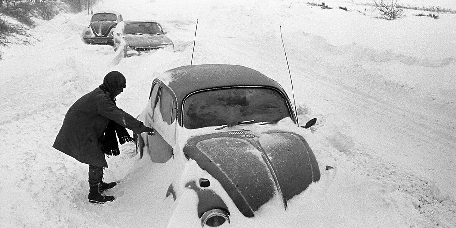 Ein Autofahrer macht sich in Cuxhaven an seinem VW Käfer zu schaffen, der im Schnee stecken geblieben ist. Aufgenommen Silvester 1978.