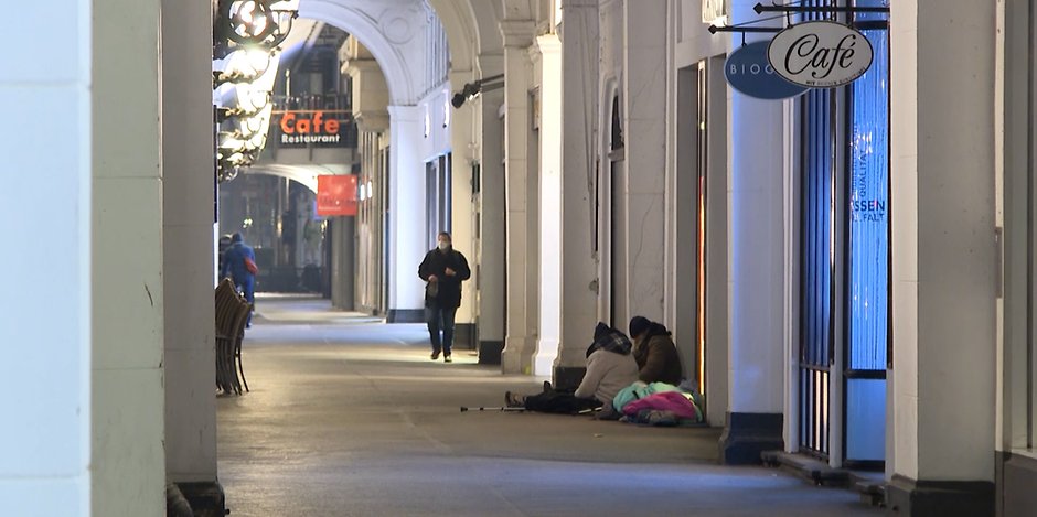 Bei bitterer Kälte sitzen zwei Obdachlose in einer Hamburger Passage auf dem kalten Steinboden. Einer von ihnen braucht Krücken zum Gehen.