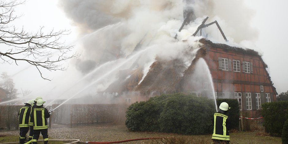 Das Dach des historischen Reetdach-Haus steht in Flammen.