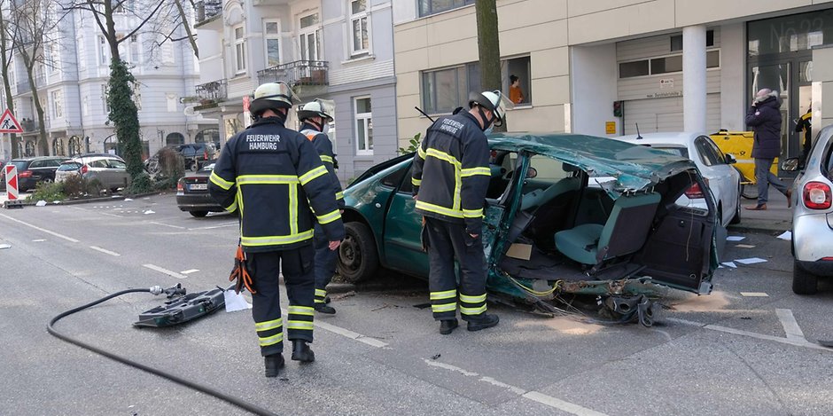 Einsatzkräfte begutachten das beschädigte Auto nach dem Unfall in Hamburg.