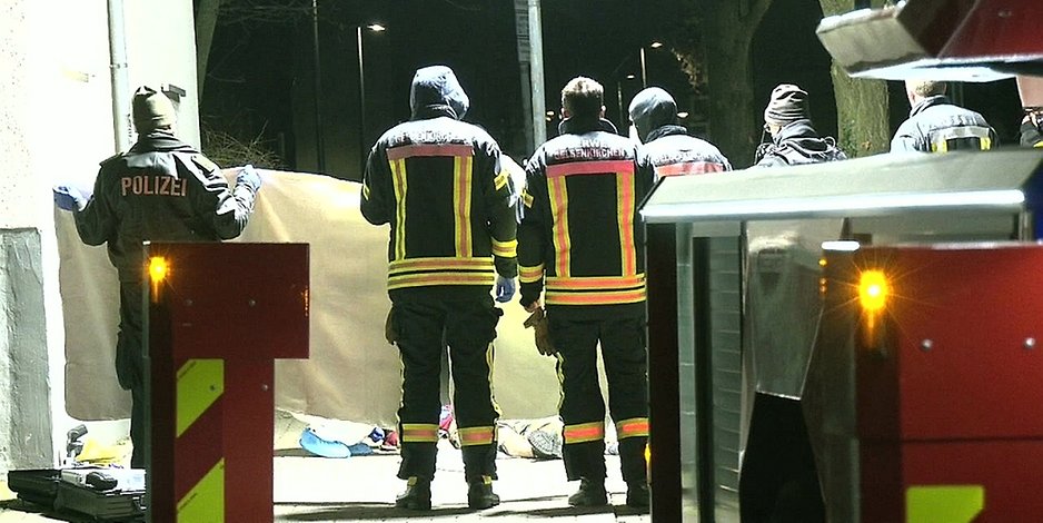Feuerwehrleute und Polizisten halten einen Sichtschutz am Tatort in Gelsenkirchen.