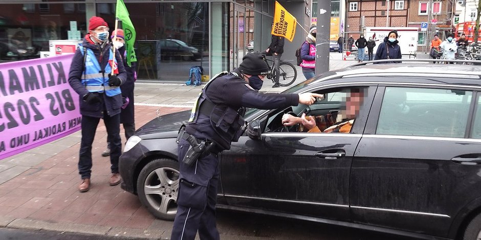 Ein Polizist weist den Mercedesfahrer zurecht.