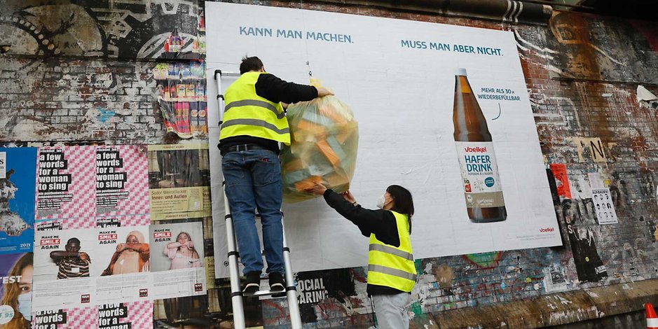Künstler hängen den mit Tetra Pak gefüllten Müllbeutel auf.