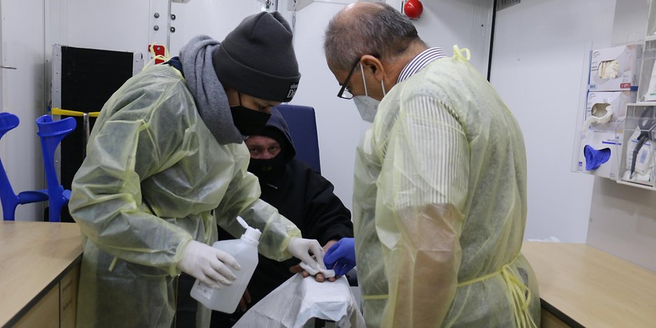 Helferin Diana Müller (links) und Arzt Dr. Hassan Ied (rechts) versorgen die Wunde eines Obdachlosen.