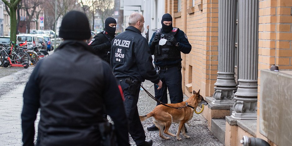 Polizisten dringen mit Hund bei einer Großrazzia in Berlin in ein Haus ein (18.2.2021).