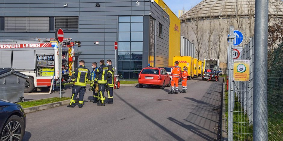 Einsatzkräfte der Feuerwehr stehen vor einem Logistikzentrum in Leimen (Rhein-Neckar-Kreis). 