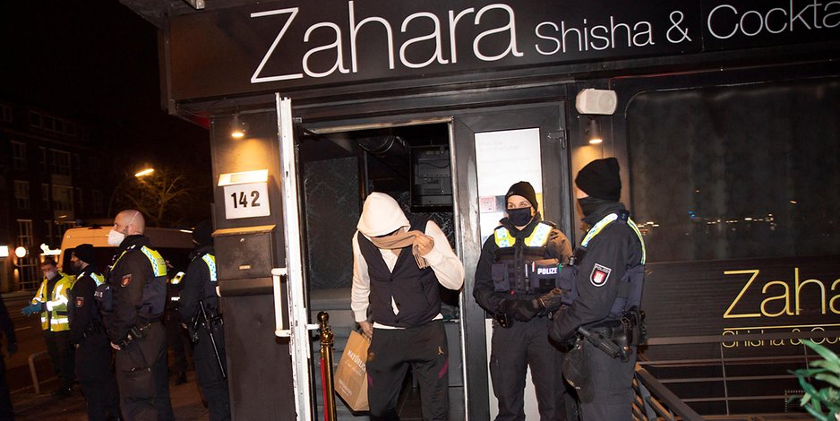 Hamburg-Wandsbek: Ein Partygast verlässt unter Aufsicht der Polizei die Shisha-Bar.