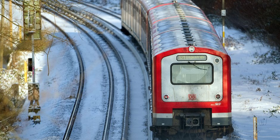 Eine S-Bahn fährt in Hamburg über schneebedeckte Gleise.