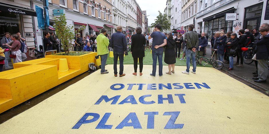 Passanten, Anwohner und Vertreter der Stadt stehen bei der Eröffnung des sechsmonatigen Verkehrsversuchs „Ottensen macht Platz“ auf der Ottensener Hauptstraße.