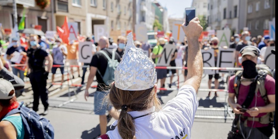 Eine Teilnehmerin der Corona-Demo am Samstag in Berlin richtet ihr Handy auf die Gegendemonstranten.