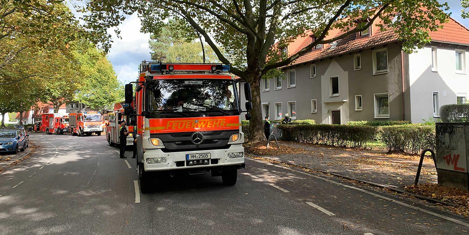 Mehrere Feuerwehr-Fahrzeuge parken vor dem Wohnhaus in Hamburg-Wandsbek.