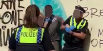 Auf dem Screenshot ist zu sehen, wie die Hand eines Polizisten in Richtung Hals des Jugendlichen greift. 