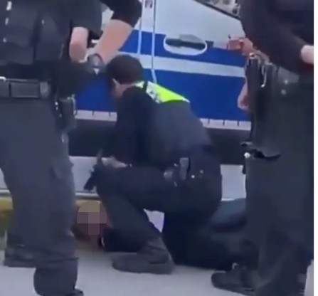 Ein Polizist fixiert den Jugendlichen am Boden.