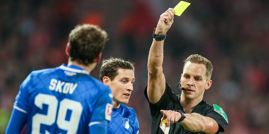 Schiedsrichter Sören Storks zeigt Hoffenheims Robert Skov die Gelbe Karte.