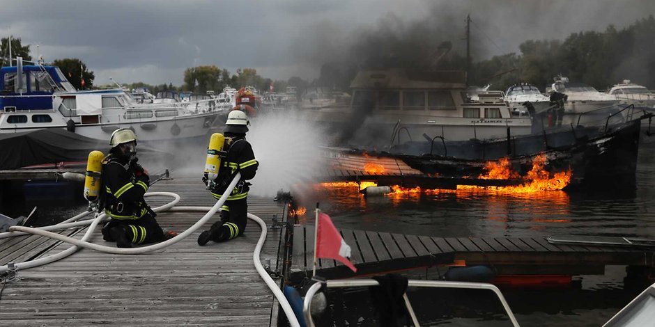 Feuerwehrleute löschen eins der brennenden Boote.