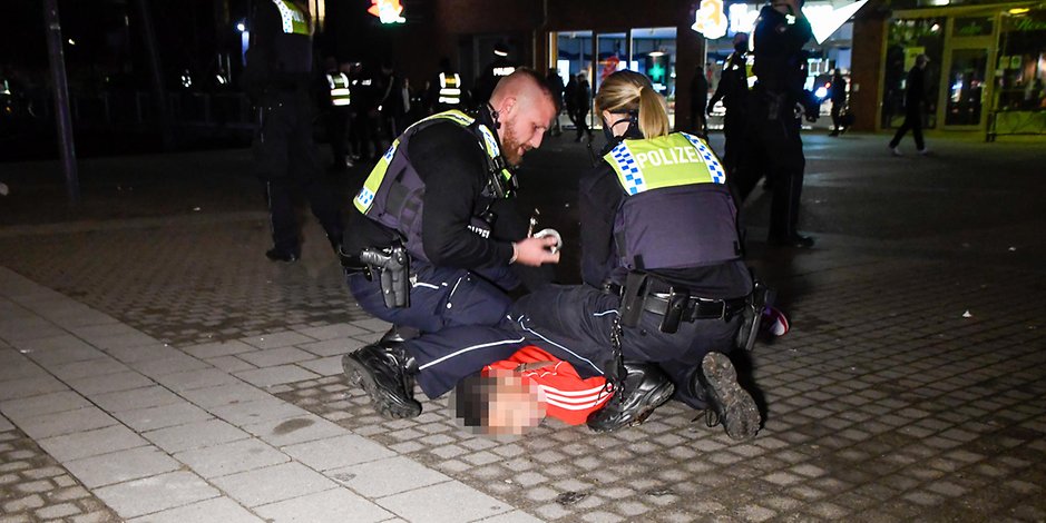 Polizisten fixieren einen Jugendlichen am Boden.