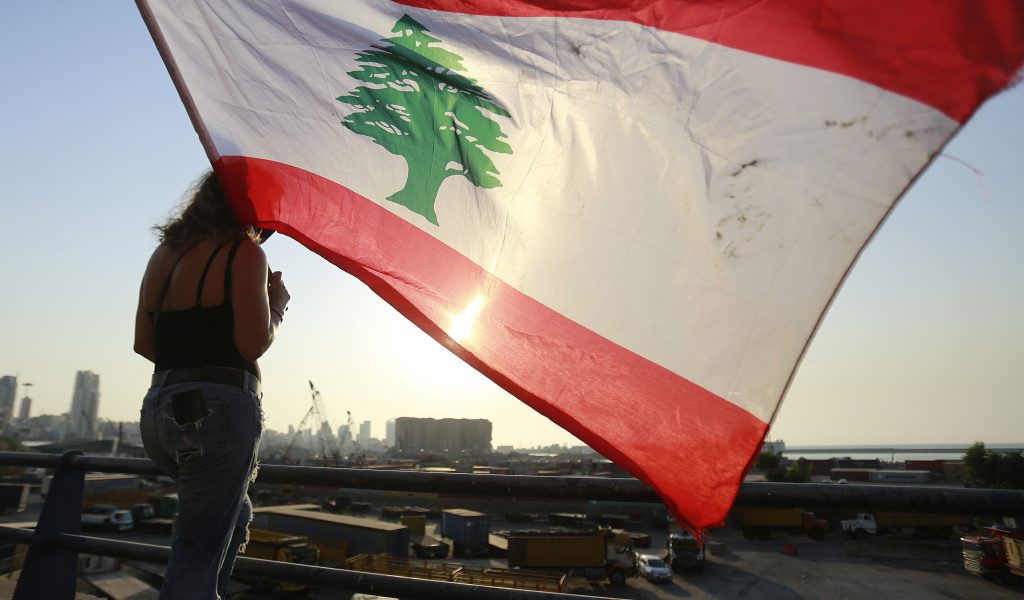Eine Demonstrantin steht mit einer Flagge Libanons am Jahrestag auf einem Dach in Beirut.