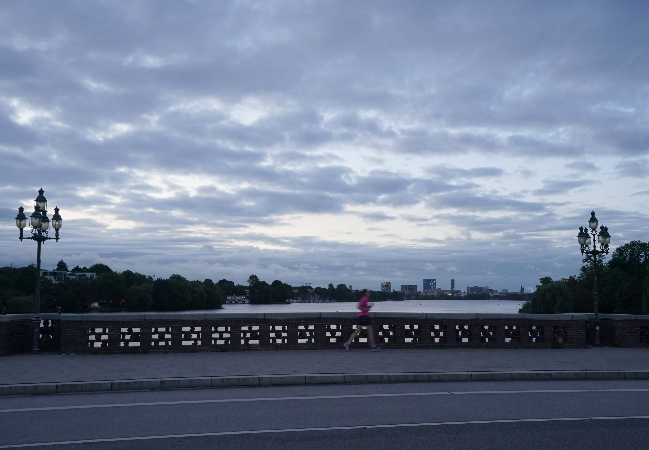 Eine Joggerin läuft im Morgengrauen über die Krugkoppelbrücke an der Außenalster.