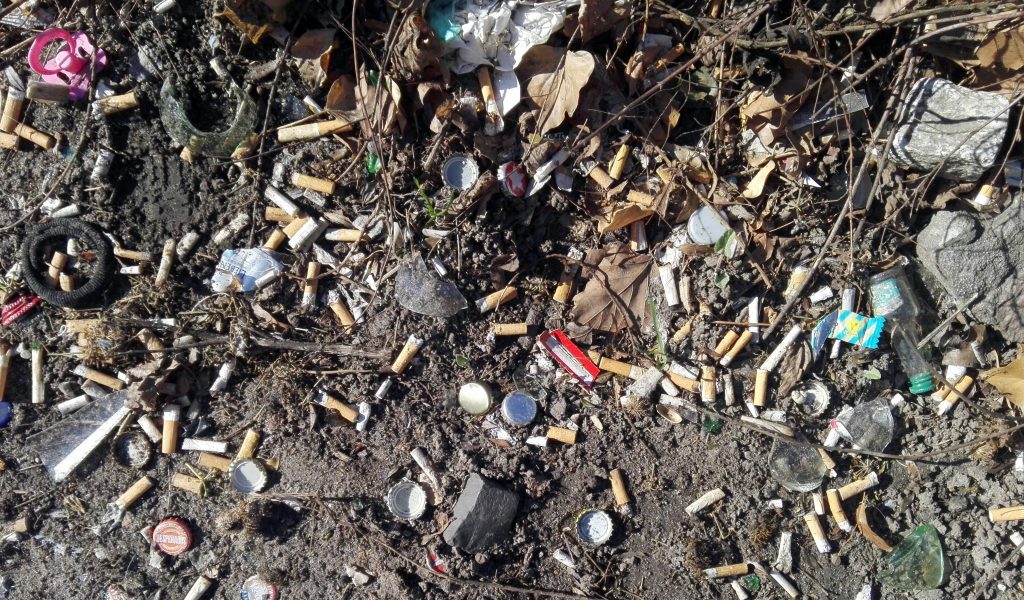 Zigaretten-stummel und Kronkorken liegen auf der Straße