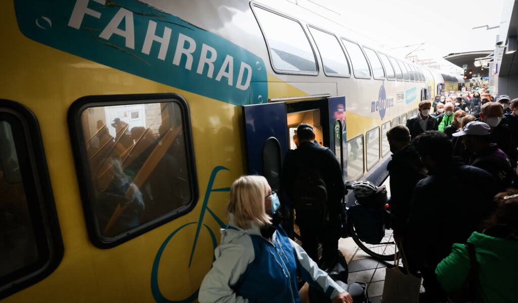 Zahlreiche Reisende, teilweise mit Fahrrad, sind am Bahnsteig neben einem Metronom-Regionalzug im Hauptbahnhof zu sehen.