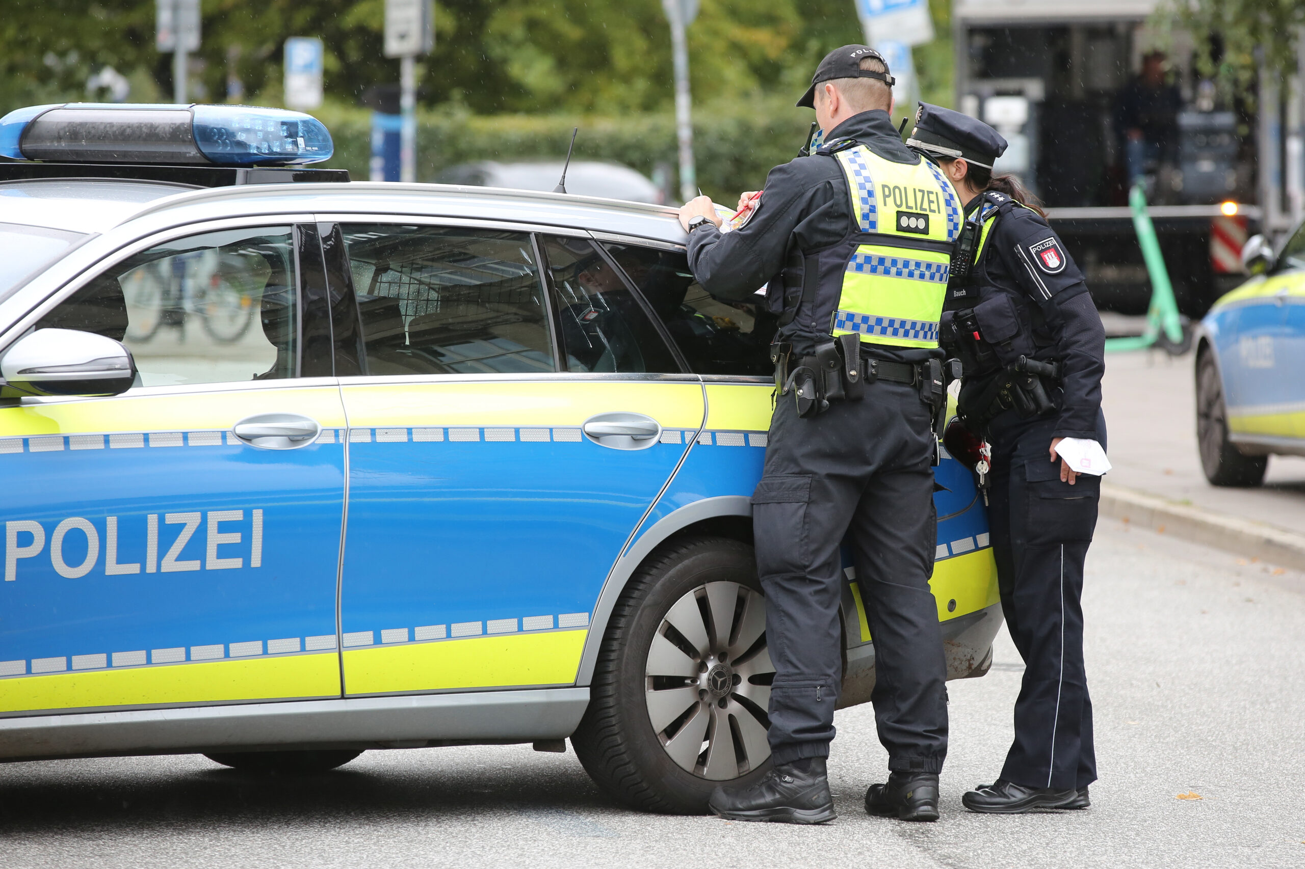 Zwei Hamburger Polizisten stehen vor einem Einsatzfahrzeug. (Symbolbild)