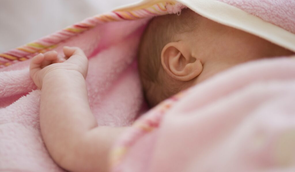 Schlafendes Baby unter einer rosafarbenen Decke