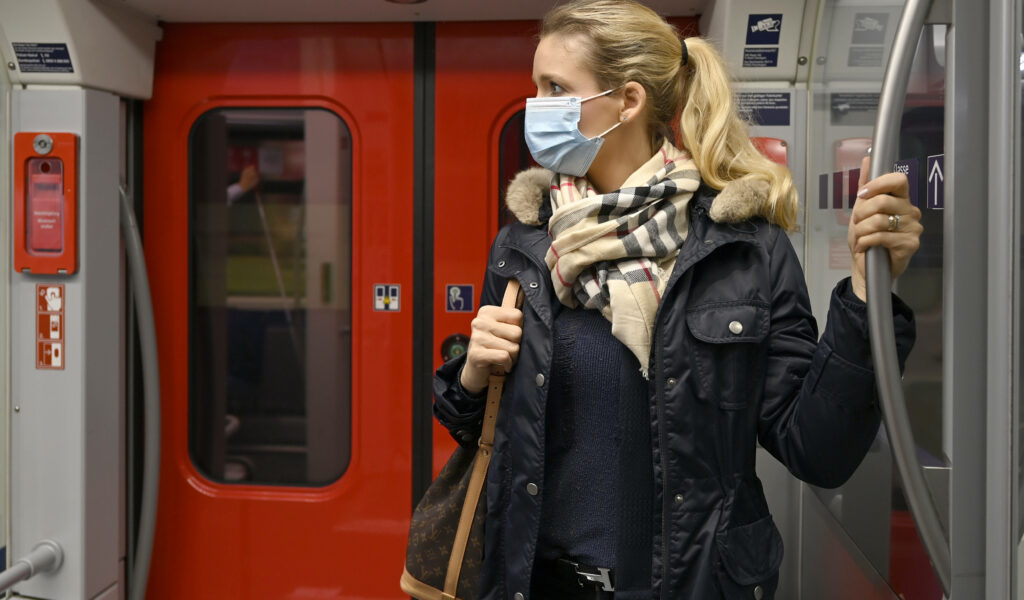 Eine Frau steht mit einer Schutzmaske in einer S-Bahn
