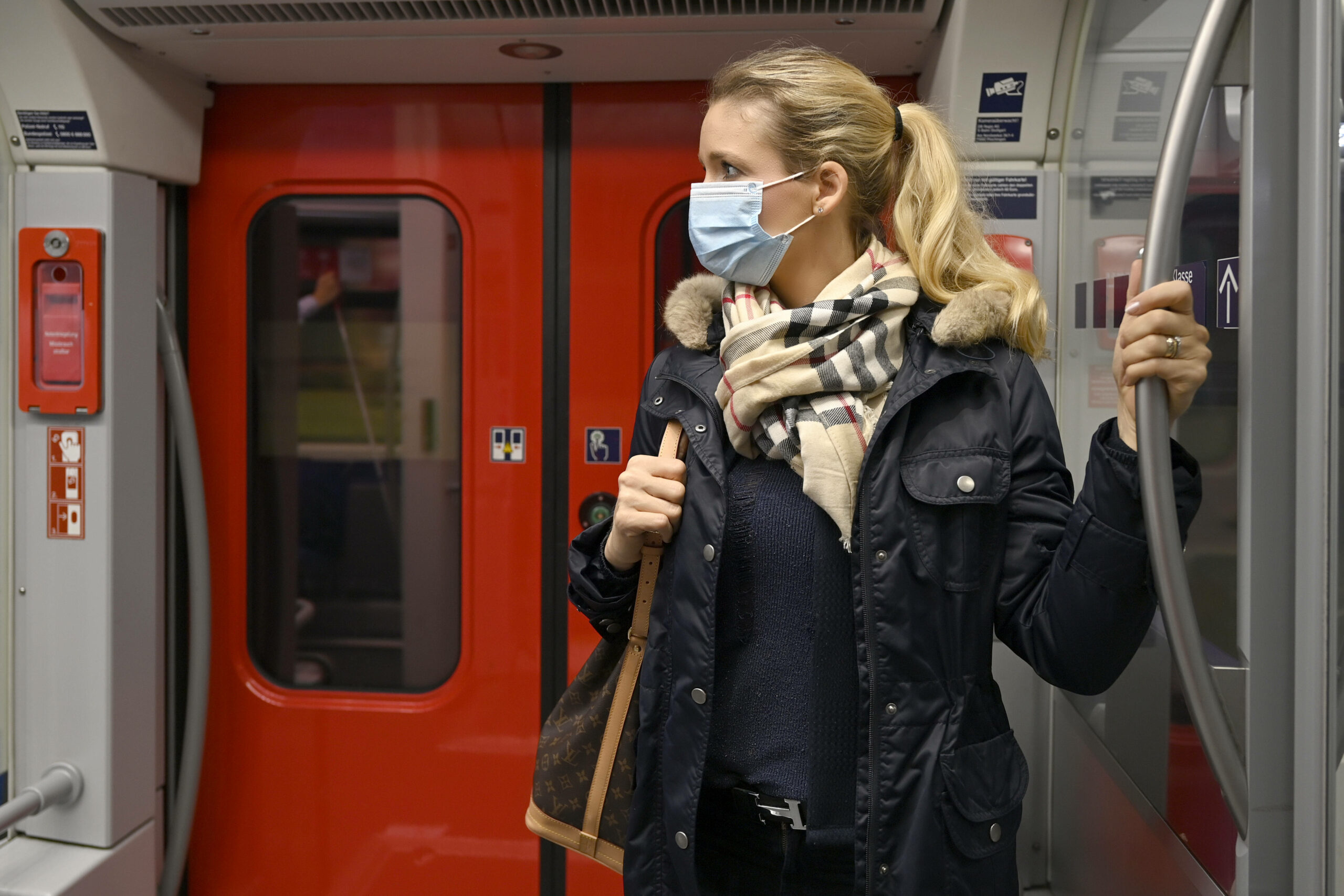 Eine Frau steht mit einer Schutzmaske in einer S-Bahn