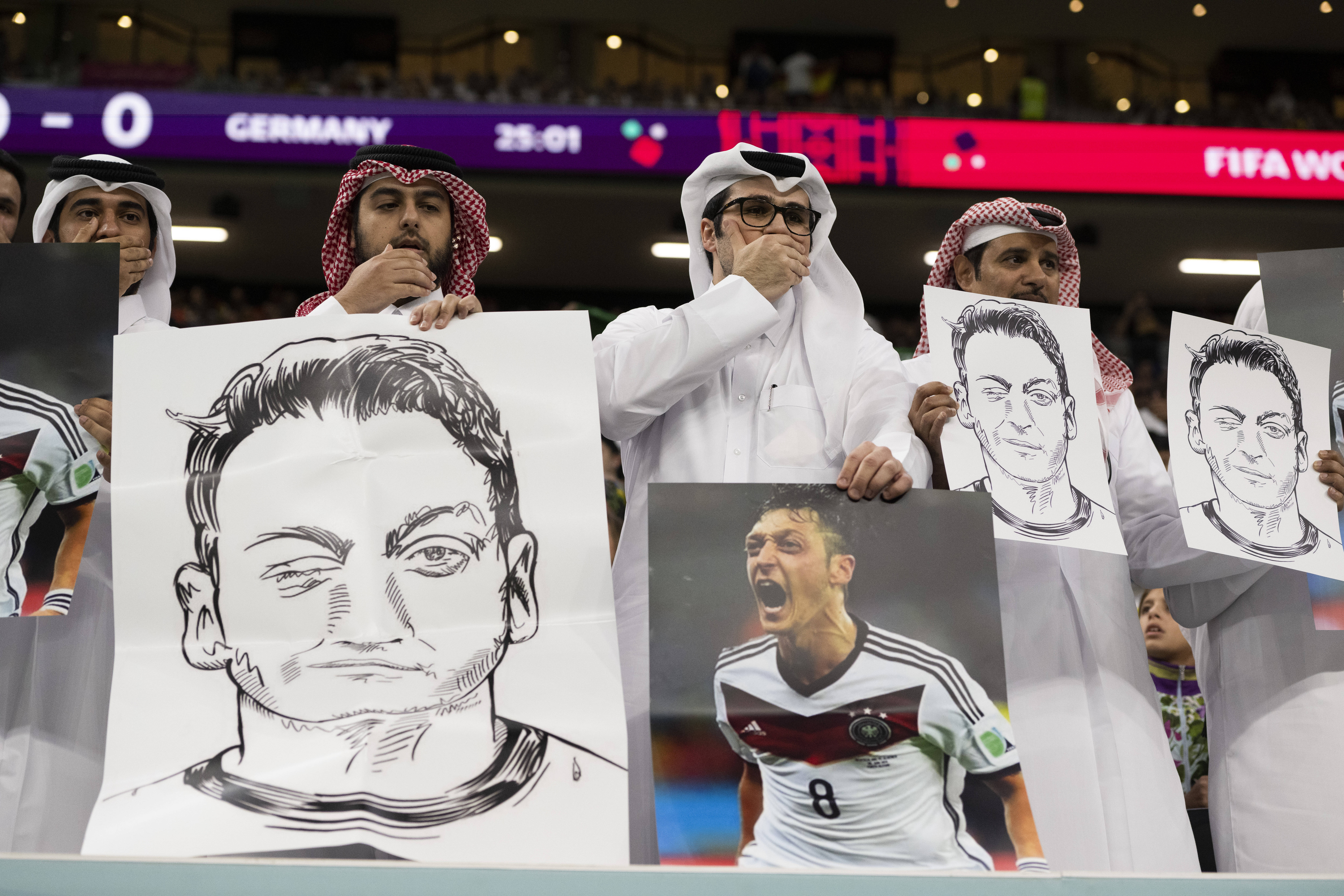 Katarer zeigen Özil-Bilder und die Mund-zu-Geste.