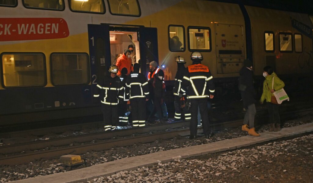 Feuerwehrkräfte führen die Fahrgäste aus dem Zug.