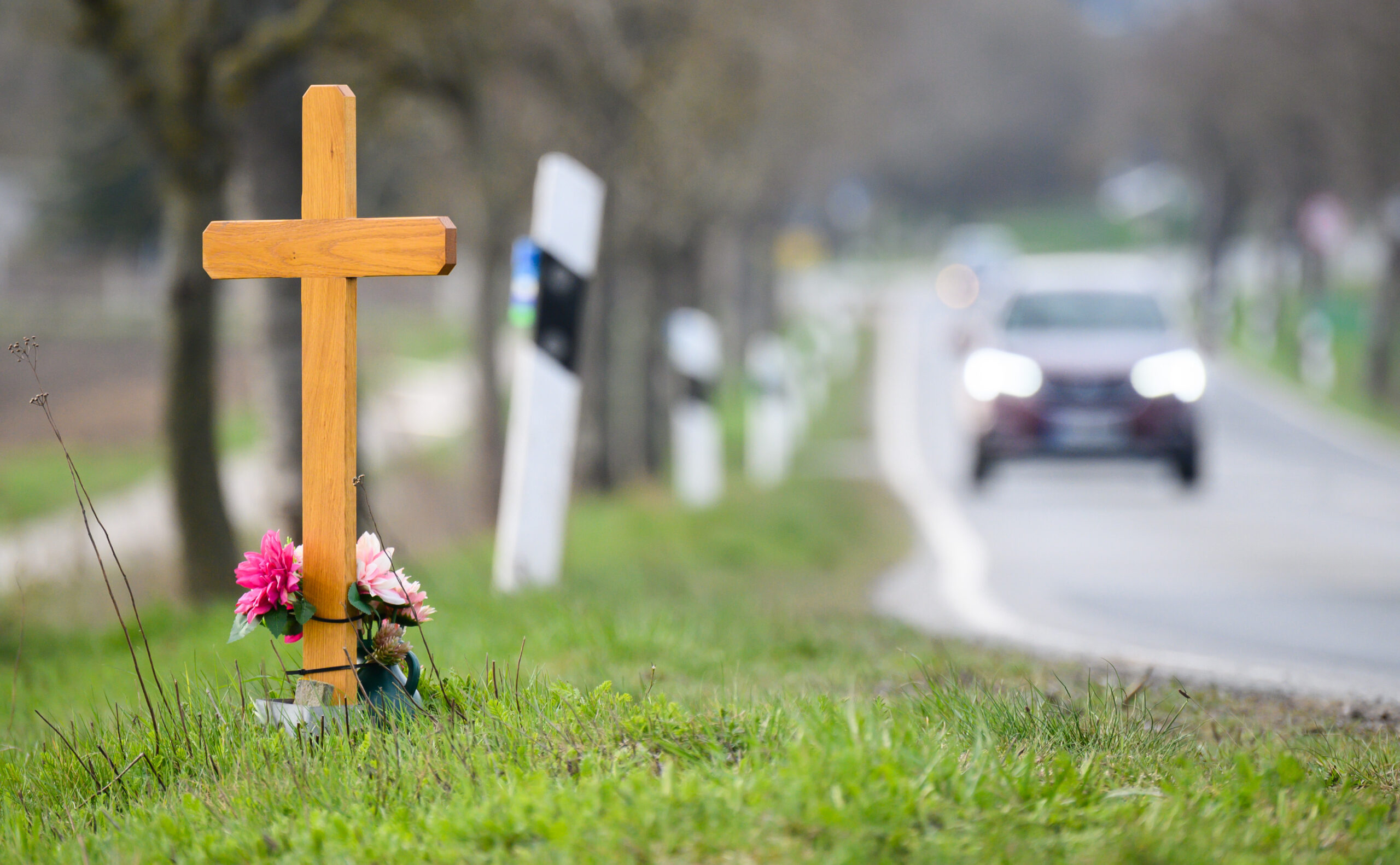 Ein Kreuz steht auf dem Grünstreifen einer Landstraßen.