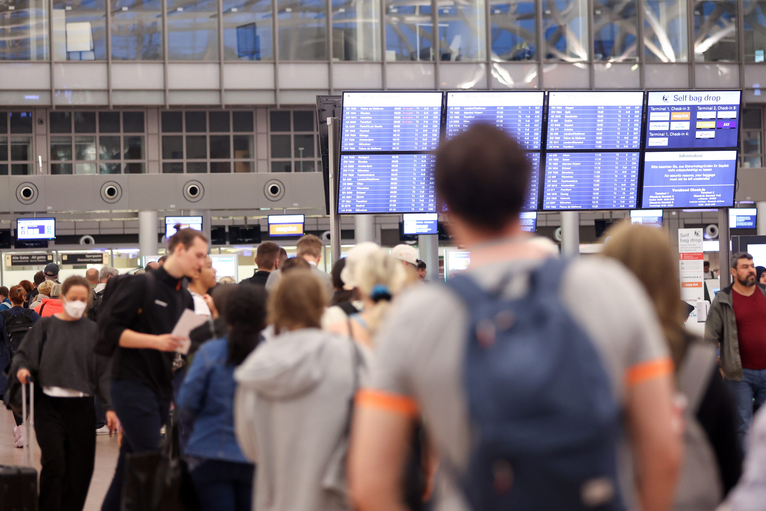 Zahlreiche Reisende stehen am Morgen in einer Schlange im Terminal 1 an, die zur Sicherheitskontrolle am Hamburger Flughafen führt. (Archivbild)