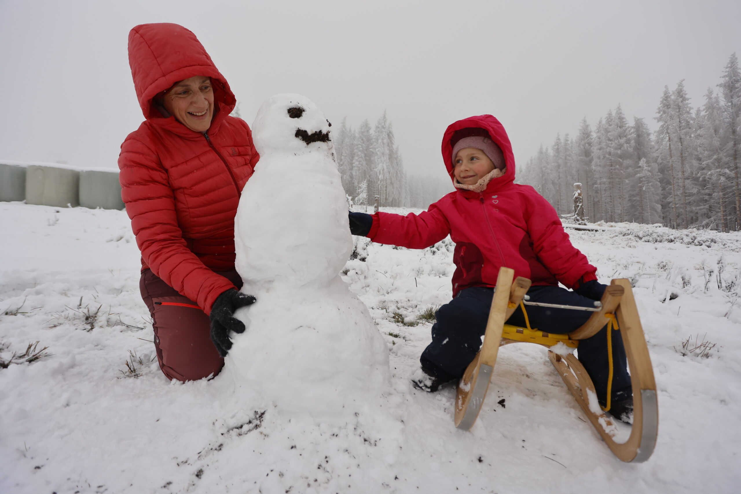Eine Frau baut mit ihrer Tochter einen Schneemann am Hexenritt in Braunlage.