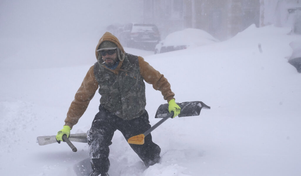 In Buffallo im Bundesstaat New York lag bis zu 70 Zentimeter Schnee. Travis Sanchez stapft mit zwei Schaufeln über eine Schneewehe, um einen gestrandeten Autofahrer auf der Chenango Street zu helfen.