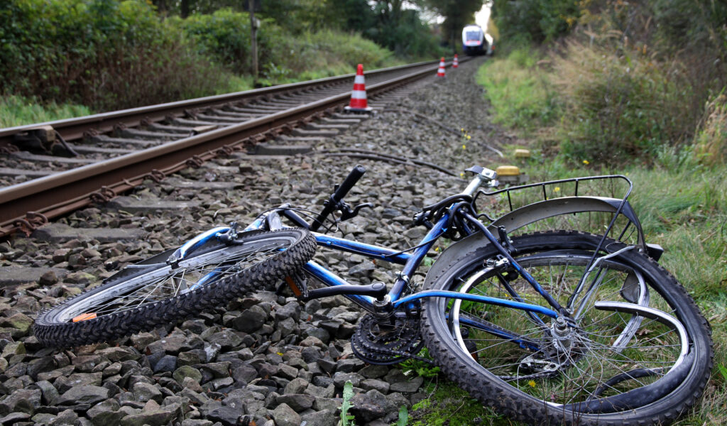 Ein völlig demoliertes Fahrrad liegt neben einem Bahngleis