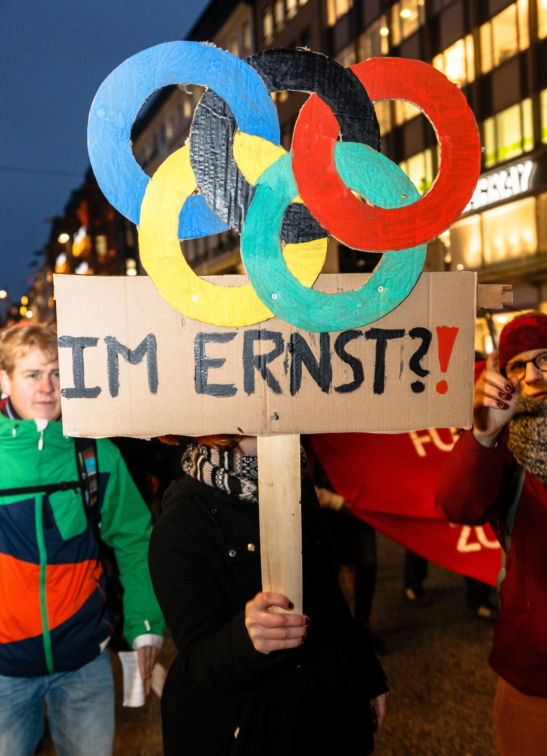 Eine Frau hält ein Schild mit den olympischen Ringen und „Im Ernst“ hoch