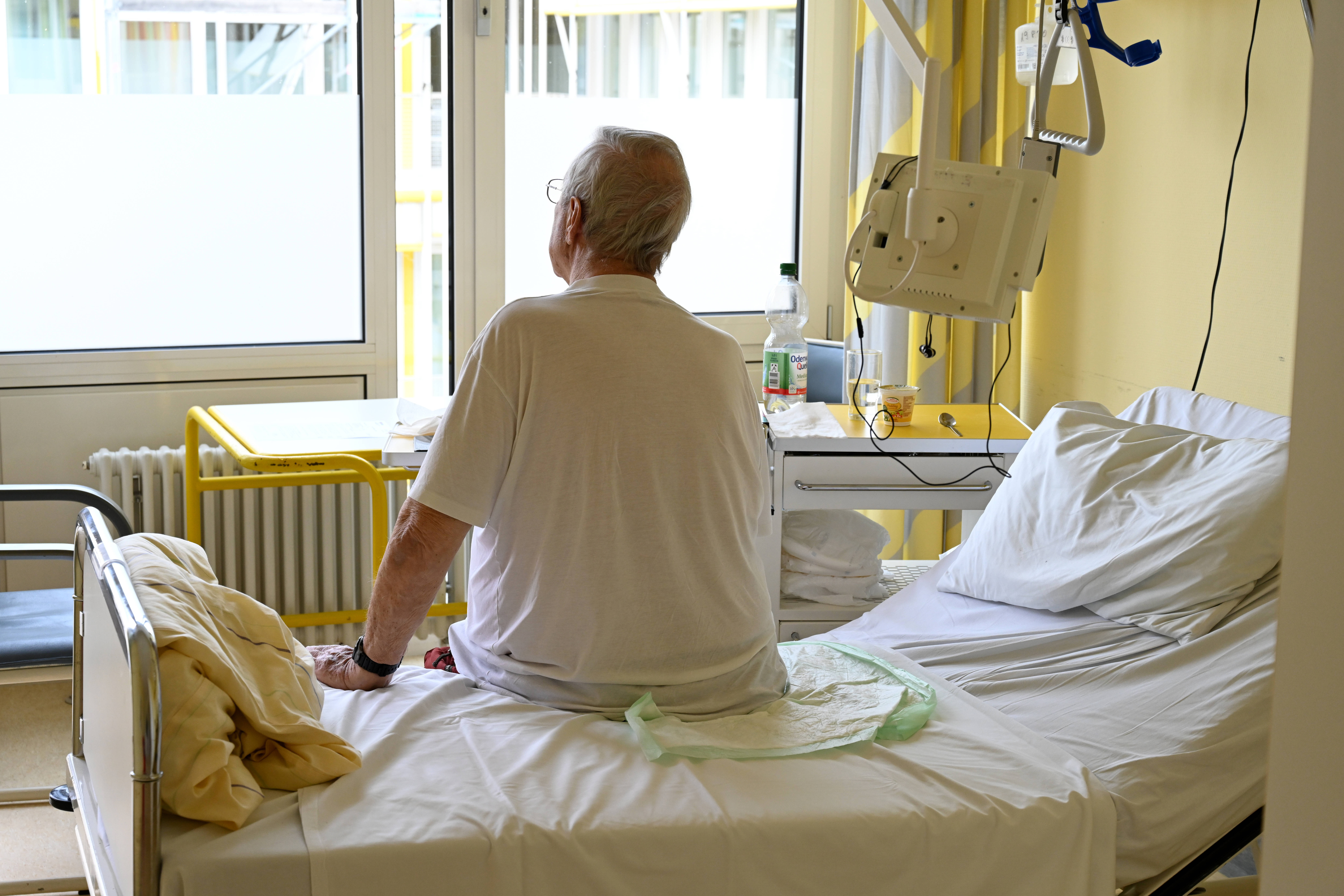 Mann sitzt auf Krankenhausbett