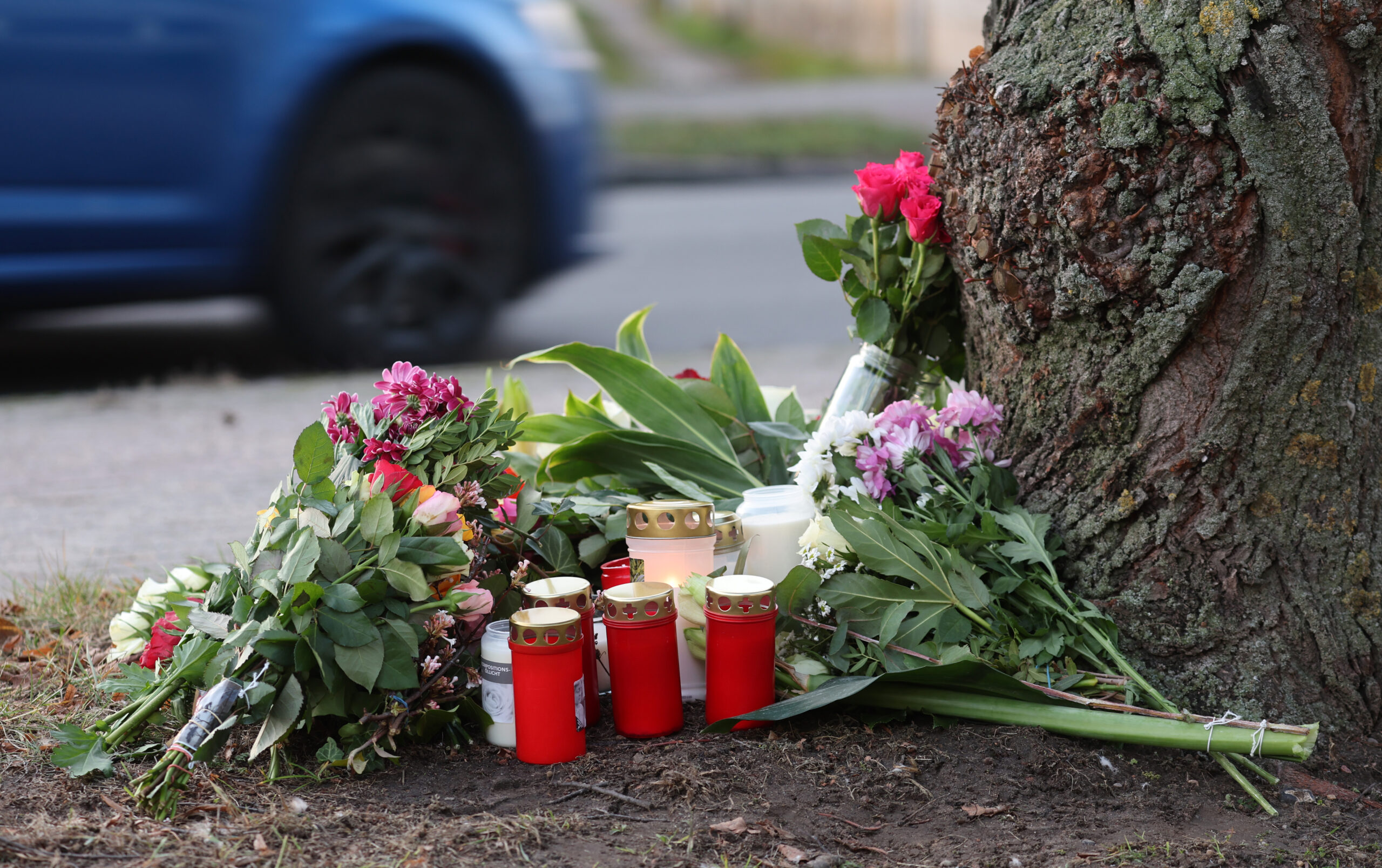 Blumen, Kerzen und Grablichter stehen am Straßenrand an einem Baum, wo am Morgen des 26.12.2022 eine 23-jährige Frau tot gefunden wurde.