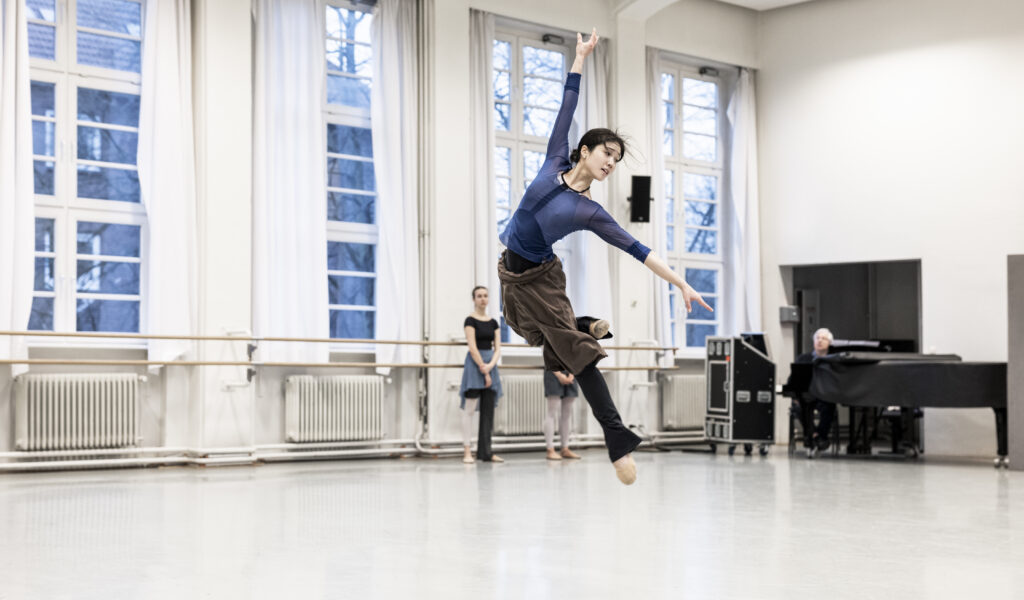 Eine Tänzerin schwebt nach einem Sprung im Ballettsaal in der Luft