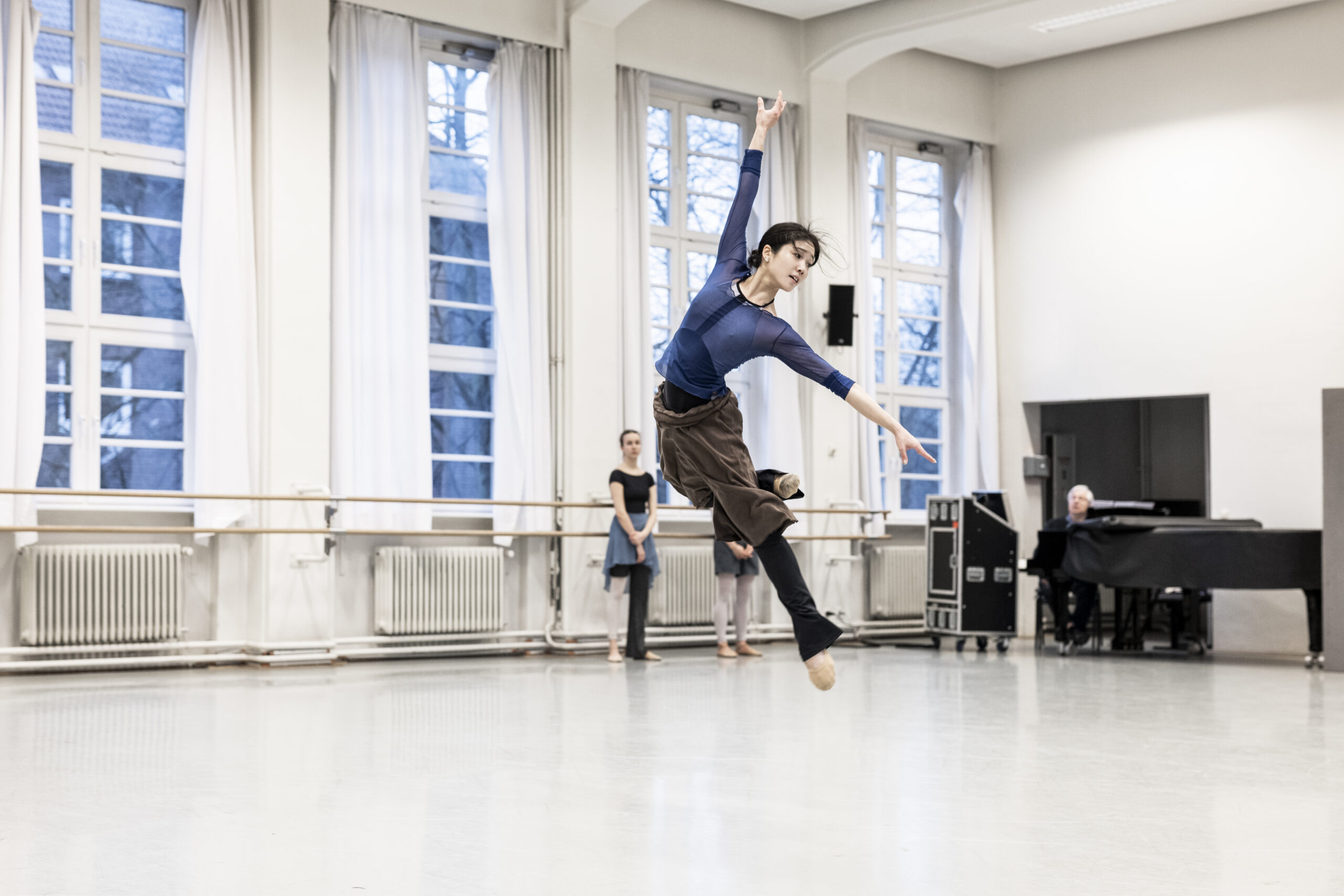 Eine Tänzerin schwebt nach einem Sprung im Ballettsaal in der Luft