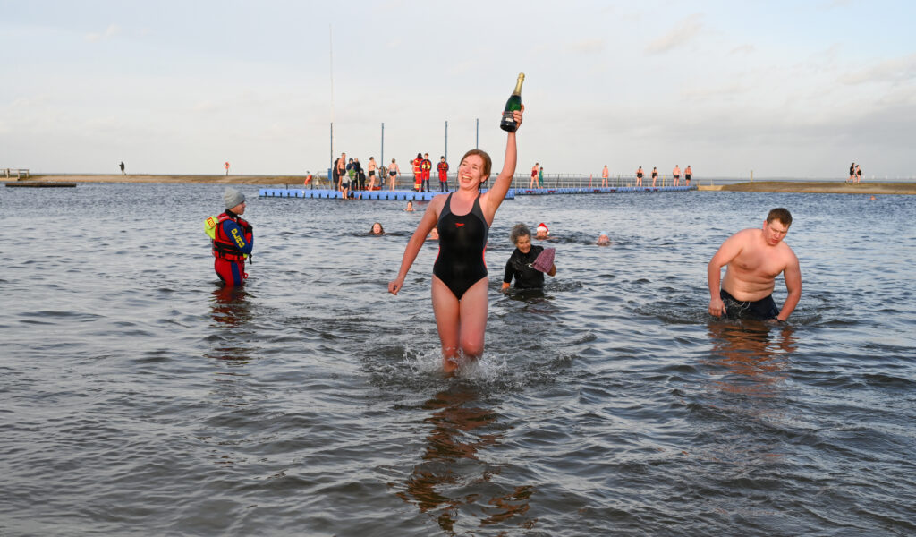 Sprung in die Nordsee zum Jahresnanfang: Eine junge Frau aus Butjadingen hat fürs Rüberschwimmen zur Badeplattform im Hintergrund eine Flasche Sekt erhalten.