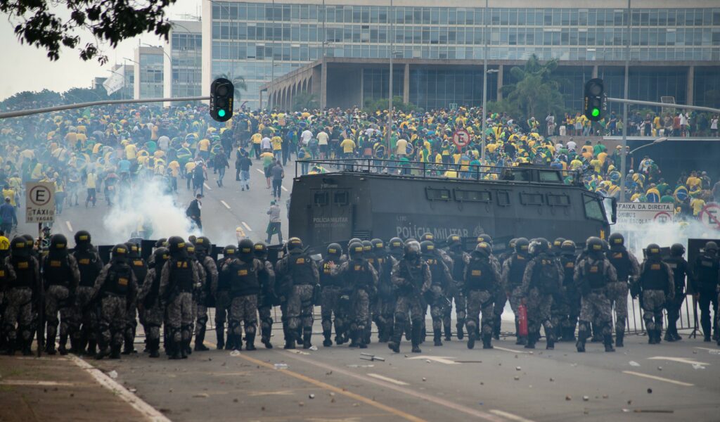 In Brasilien: Anhänger des ehemaligen brasilianischen Präsidenten Bolsonaro (hinten) geraten in der Hauptstadt mit Ordnungskräften aneinander, die Tränengasgranaten auf die Demonstranten abfeuern.