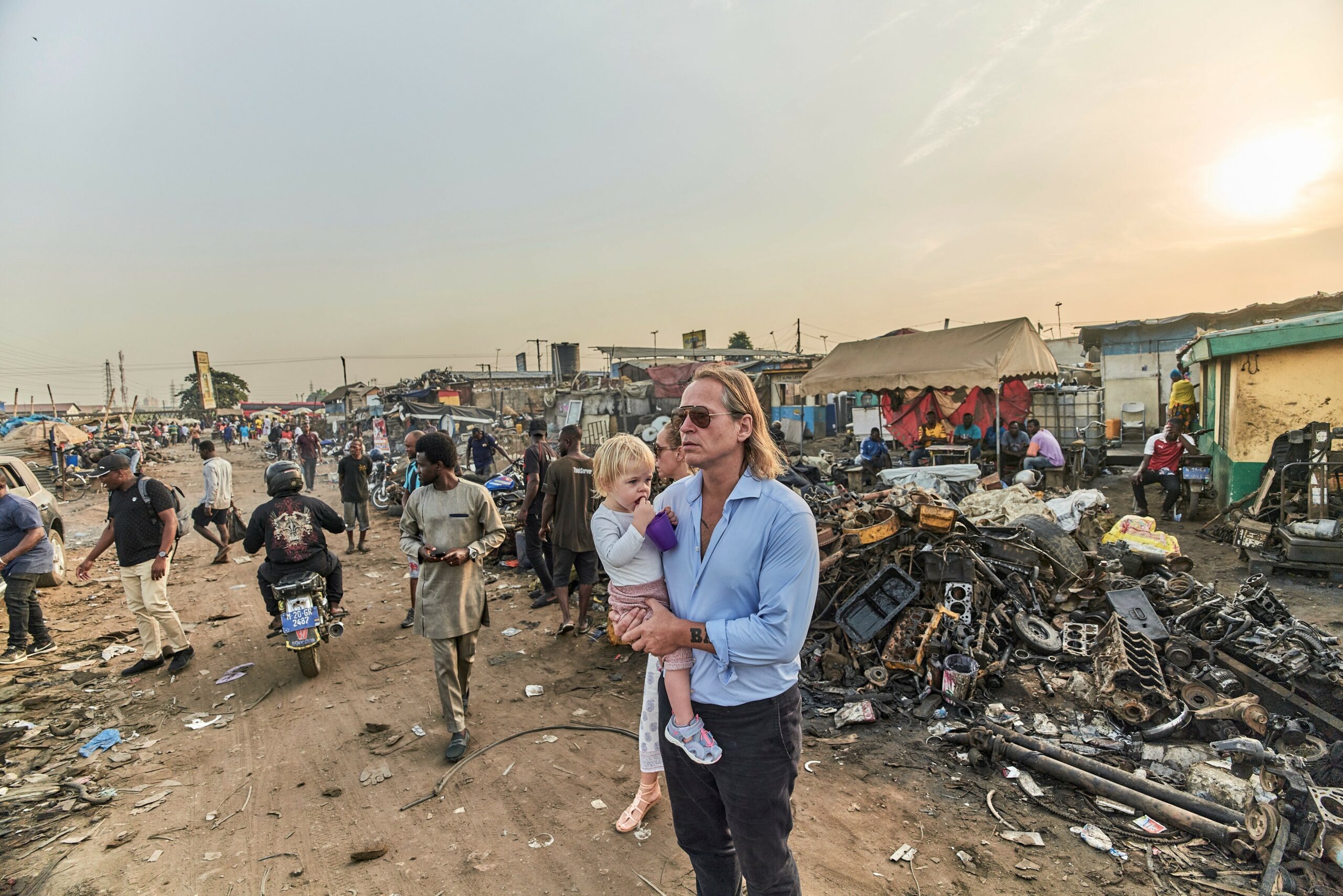 Michel Ruge steht mit seiner Tochter auf dem Arm auf einer Müllhalde.