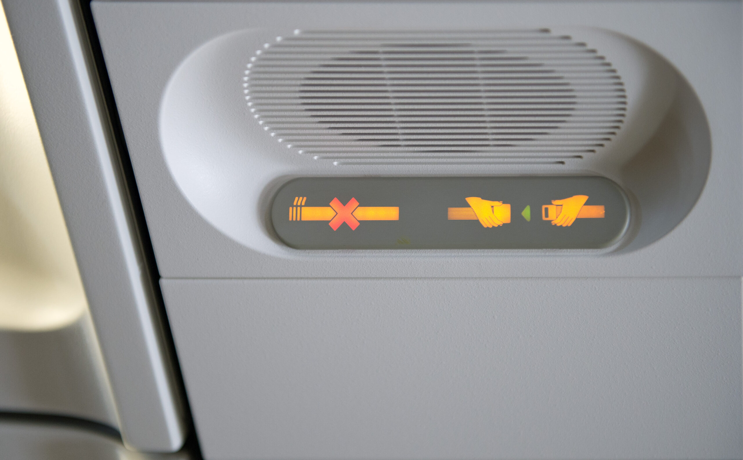 Leuchtanzeige im Flugzeug, die auf Rauchverbot und Anschnallpflicht hinweist.