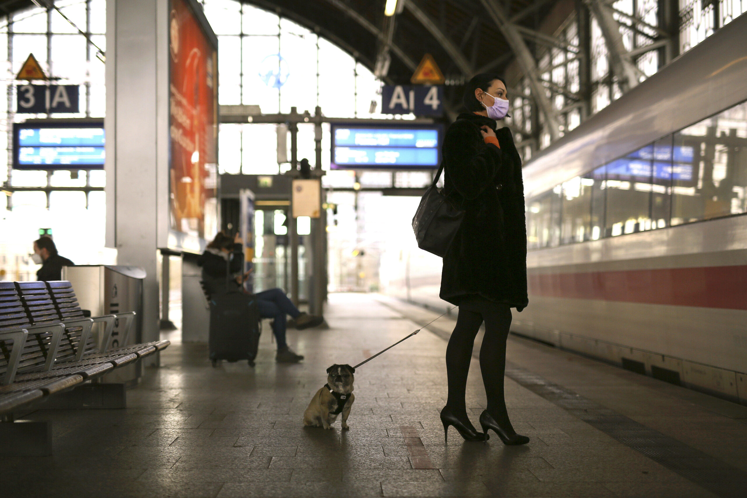 Eine Frau steht am Bahnhofsgleis, wo ein ICE einfährt